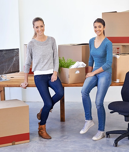 Dos empresarias con las cajas de la mudanza en la oficina.