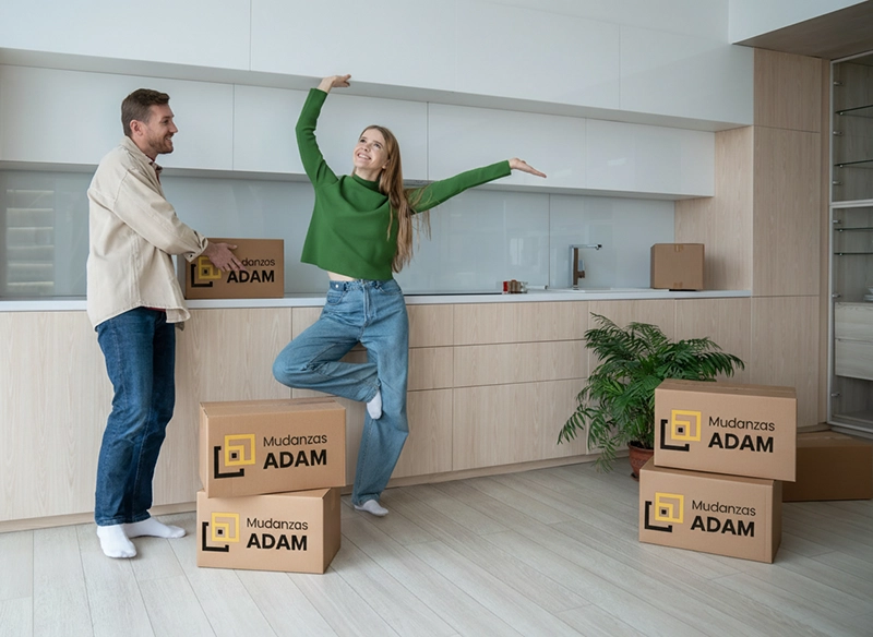 Una pareja feliz en su cocina con las cajas de la mudanza.